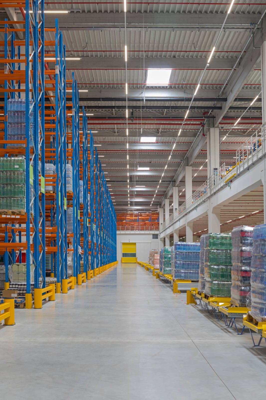 Tall storage racks and a clear central aisle inside a distribution warehouse.