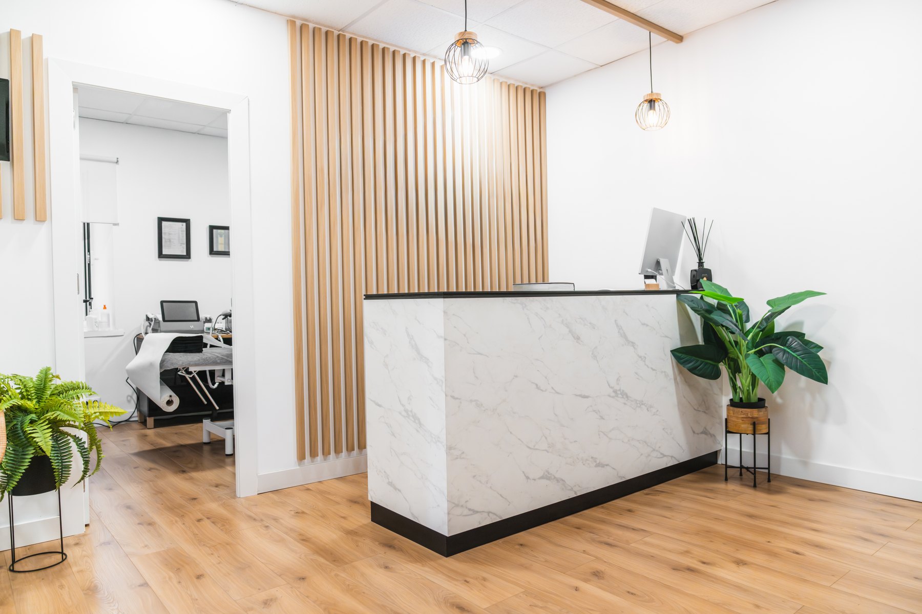 Clinic reception with a pale stone counter, timber accents and plants.