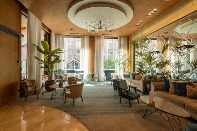 Hotel lounge with chandeliers, mirrors, indoor planting and comfortable seating