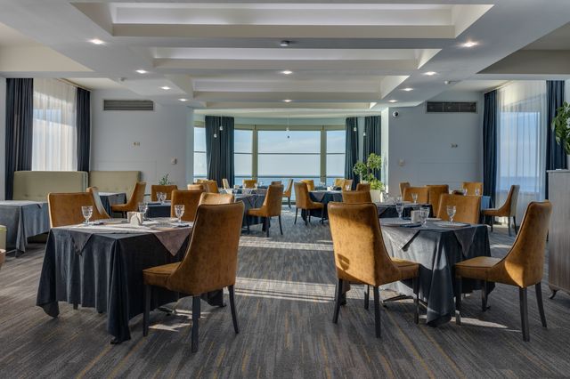 Hotel restaurant with upholstered mustard chairs, coffered ceiling and large windows