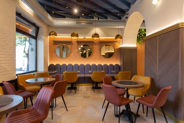 Cafe interior with yellow and pink chairs, booth seating and round decorative mirrors