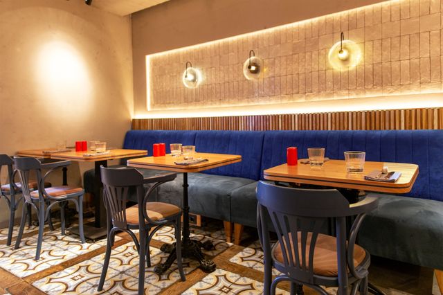 Restaurant with blue banquette seating, brass globe pendant lights and textured walls