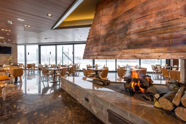 Resort restaurant with timber ceiling and a large central fireplace