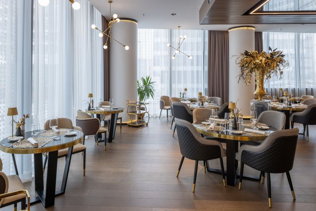 Fine-dining restaurant with brass-trimmed tables, sculptural lighting and full-height glazing
