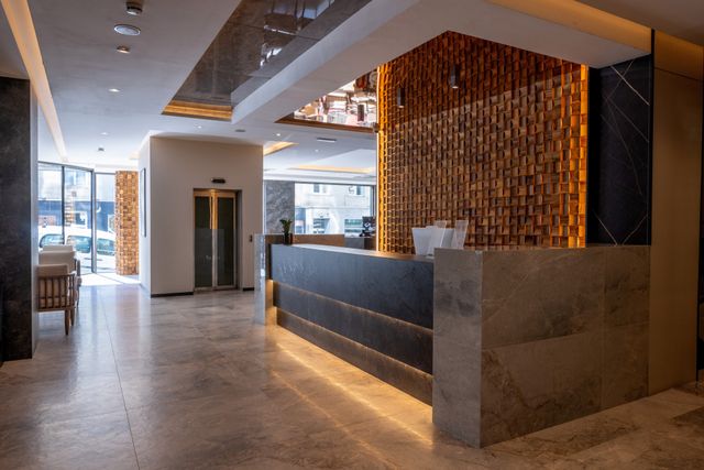 Hotel reception with a dimensional timber backdrop, stone counter and concealed lighting