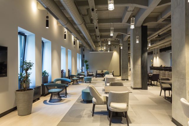 Hotel lounge with exposed ceiling services, neutral seating and open-plan dining