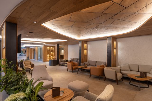 Hotel lounge with a geometric ceiling, cove lighting and neutral seating arranged in groups