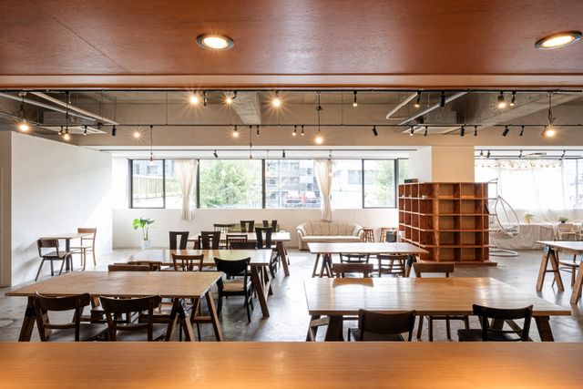 Open dining space with timber tables, mixed chairs, display shelving and ceiling-mounted track lights.