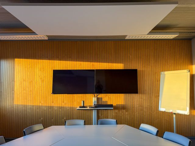 Conference table facing twin displays on a timber feature wall.