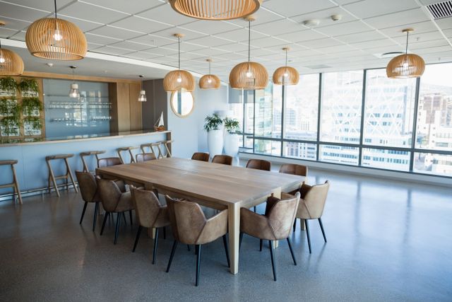 Workplace dining area with a long timber table, upholstered chairs, woven pendant lights and a bar counter.
