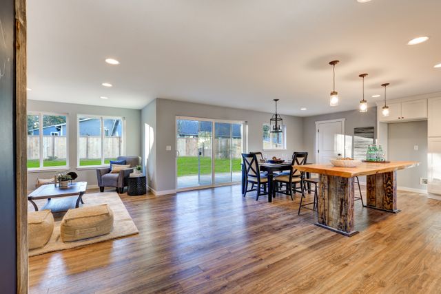 Open-plan home with timber flooring, a kitchen island, dining table and doors to the garden.