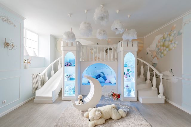 Children’s room with a castle-themed raised bed, slide, steps and decorative cloud lighting.