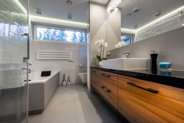 Bathroom with a wood-front vanity, countertop basin, bathtub and shower screen.