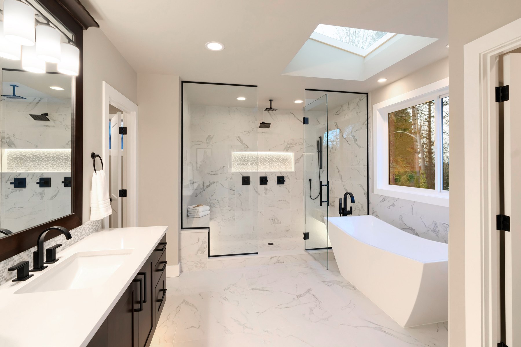 Bathroom with marble-pattern finishes, a double vanity, walk-in shower and freestanding bath.