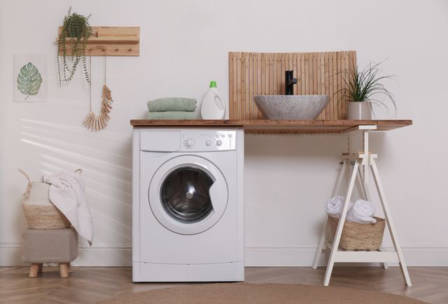 Laundry area with a front-loading washing machine, timber counter, vessel basin and woven storage.