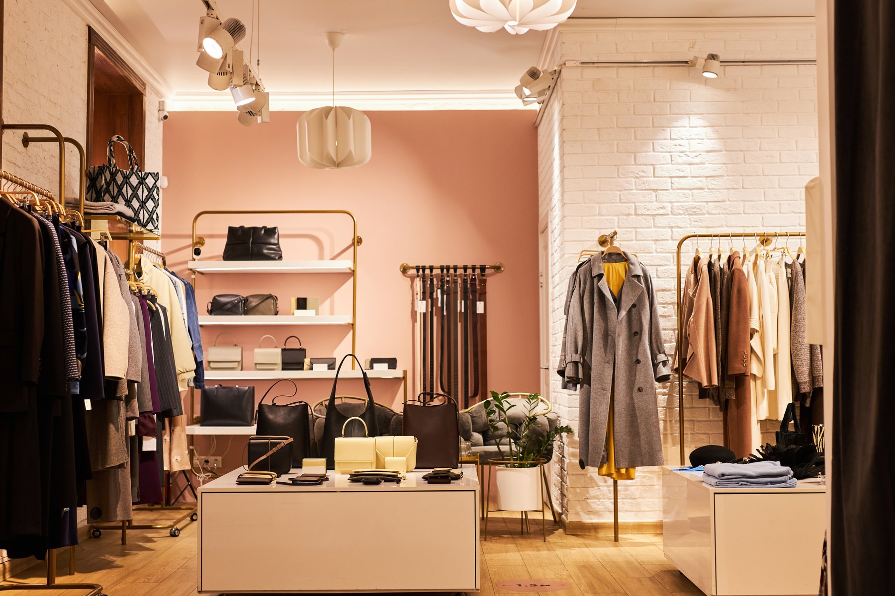 Fashion boutique with blush walls, gold rails and carefully arranged displays.
