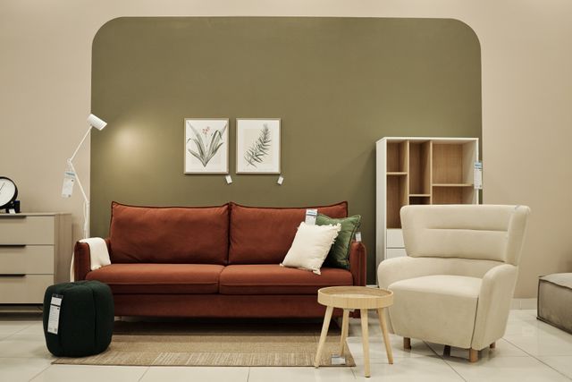 Furniture display with a brown sofa, armchair, green wall and coordinated accessories