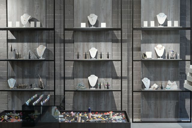 Jewellery boutique display wall with illuminated cabinetry and dark textured finishes
