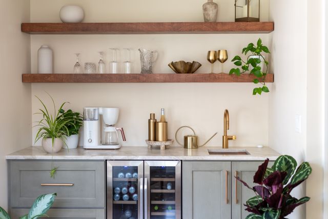 A small wet bar combines open timber shelves, a sink, drinks storage and pale cabinetry.