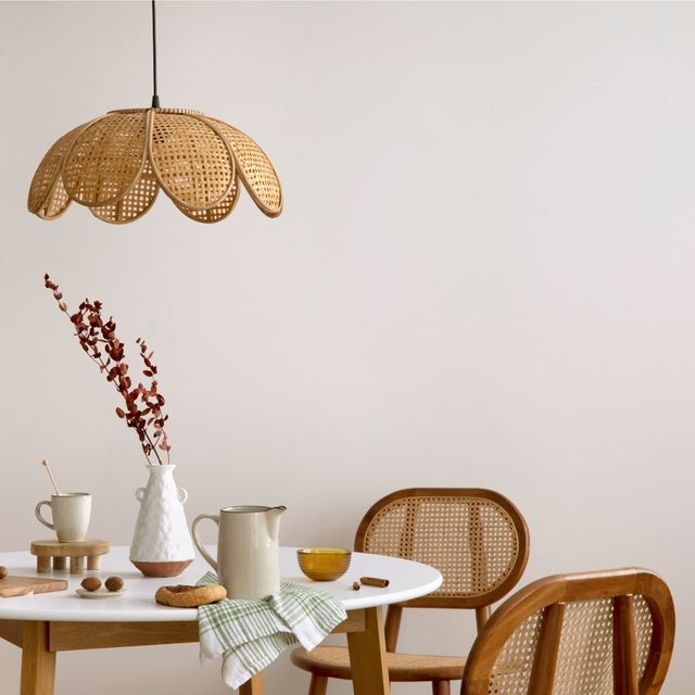 A small round table, woven chairs and a petal-shaped pendant create a light dining vignette.