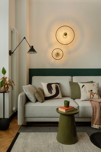 A pale sofa with patterned cushions sits beneath glowing circular wall lights and a dark accent band.