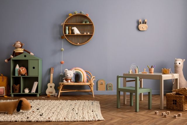 A small desk, toy storage and woven accents furnish a children's play space against a muted blue wall.