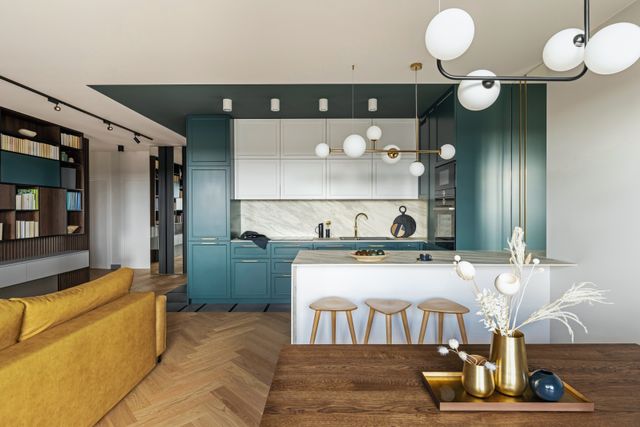 Turquoise cabinetry, a pale island and timber stools connect an open kitchen to its adjoining living area.