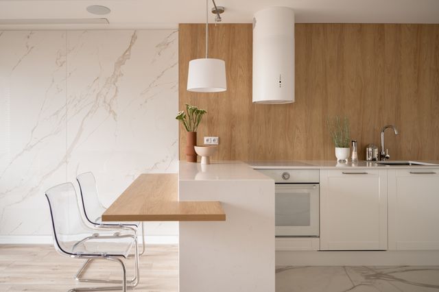 White cabinets and a pale breakfast counter are set against timber paneling and a stone-look wall.
