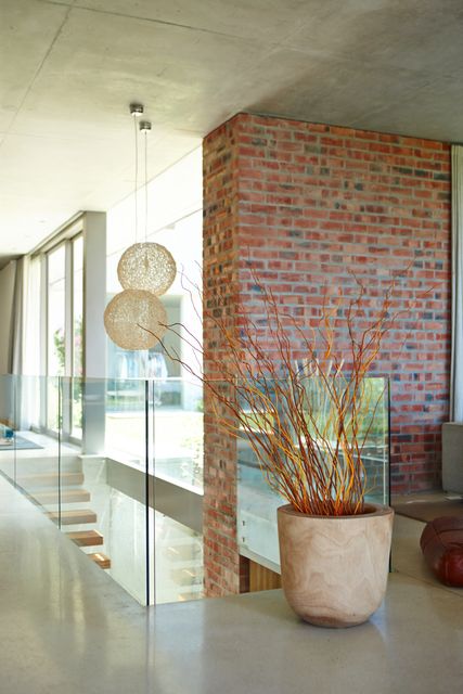 An exposed brick wall, glass balustrade and tall windows shape a light-filled entrance and stair hall.